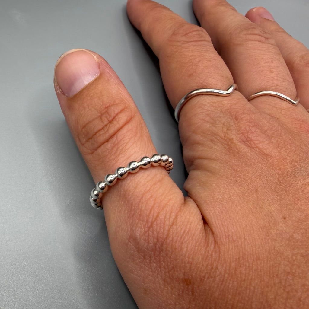 925 sterling silver beaded stacking ring worn on finger next to a wishbone ring