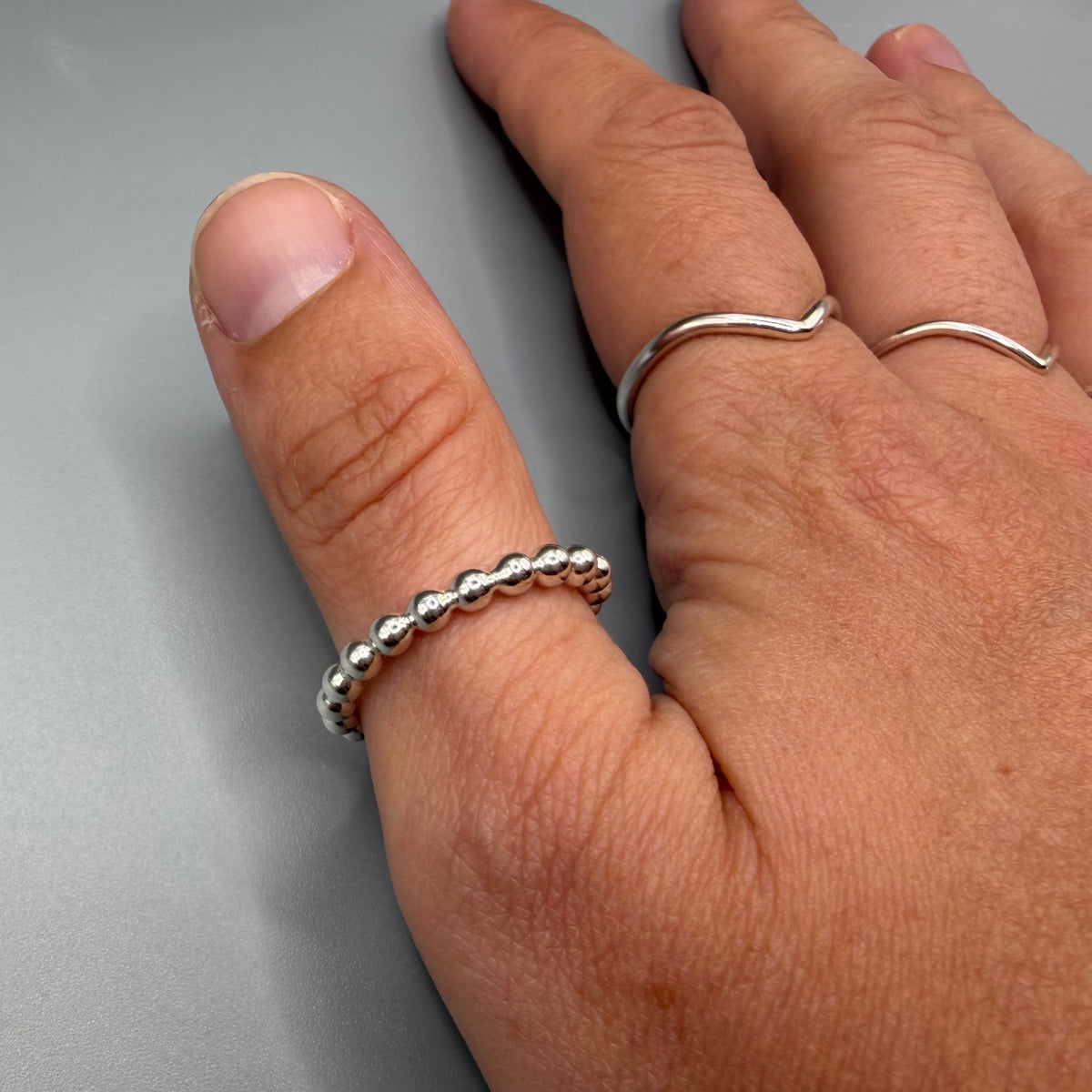 925 sterling silver beaded stacking ring worn on finger next to a wishbone ring