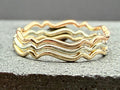 9ct gold wavy stacking ring on hand, side angle